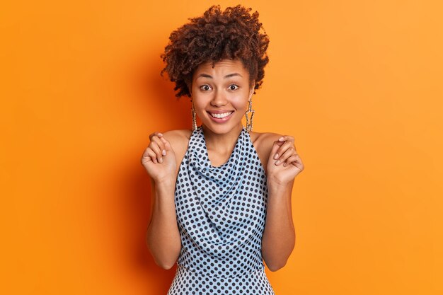 Mujer de moda positiva con el pelo rizado levanta las manos