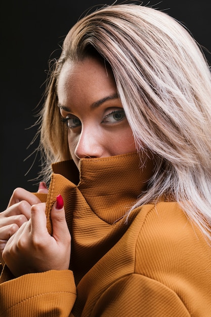 Mujer de moda que cubre su boca con chaqueta amarilla