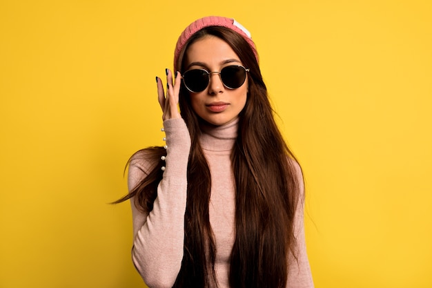 Mujer de moda en ropa de moda con gorra rosa y gafas de sol redondas