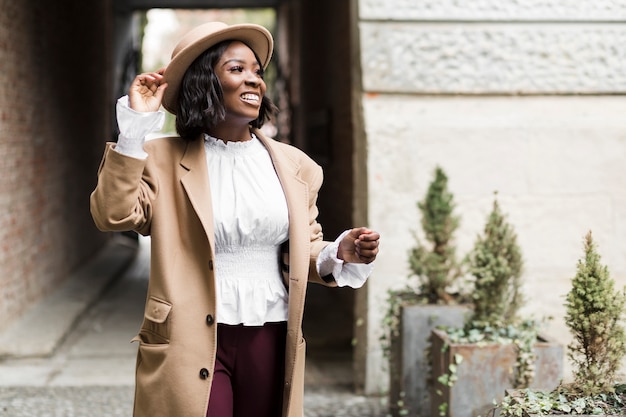 Mujer de moda sonriente posando mientras sostiene su sombrero