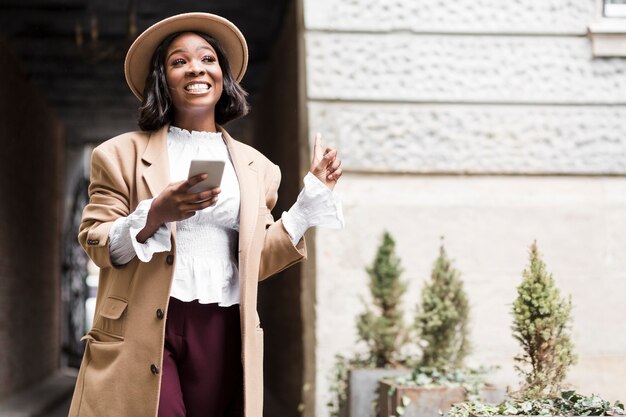 Mujer de moda sonriente que sostiene su teléfono