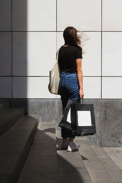 Foto gratuita mujer de moda de tiro largo con una bolsa de compras por detrás