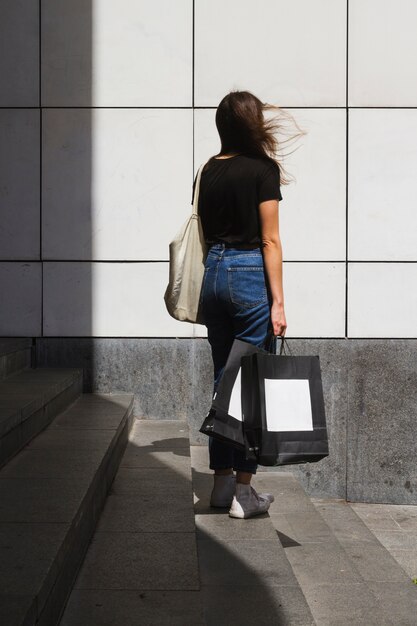Mujer de moda de tiro largo con una bolsa de compras por detrás