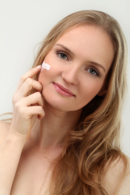 mujer modelo poses con crema para la cara