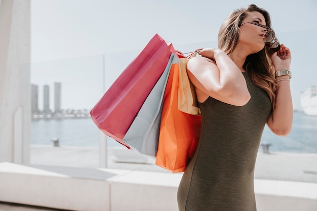 Mujer moderna con bolsas y gafas de sol