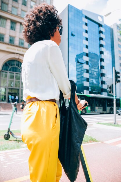 Mujer moderna en una ciudad con un patinete eléctrico