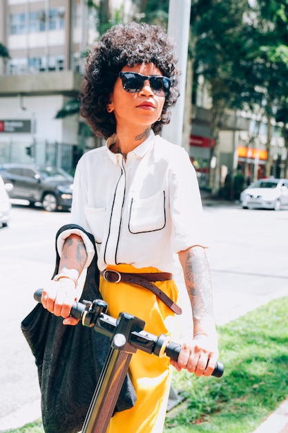 Foto gratuita mujer moderna en una ciudad con un patinete eléctrico