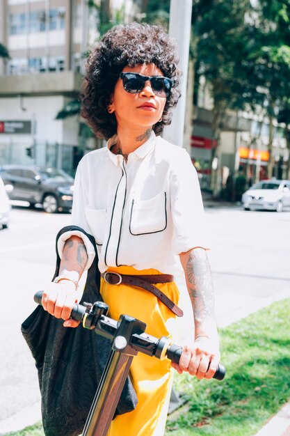 Mujer moderna en una ciudad con un patinete eléctrico