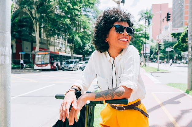 Mujer moderna en una ciudad con un patinete eléctrico