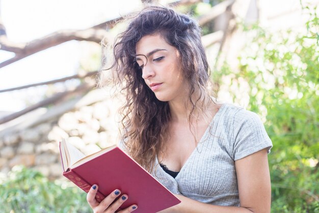 Mujer moderna leyendo un libro en el parque