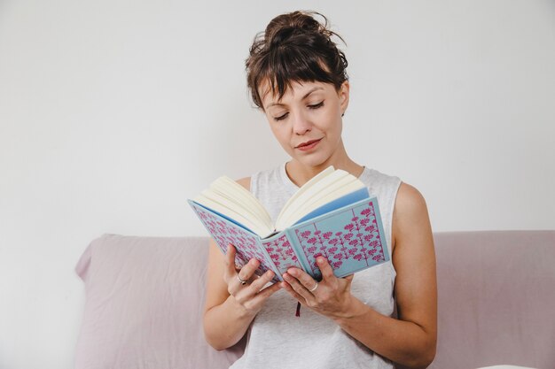 Mujer moderna leyendo un libro en el sofá