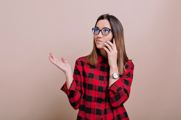 Foto gratuita mujer moderna ocupada usa gafas hablando por teléfono inteligente con verdaderas emociones os pared aislada