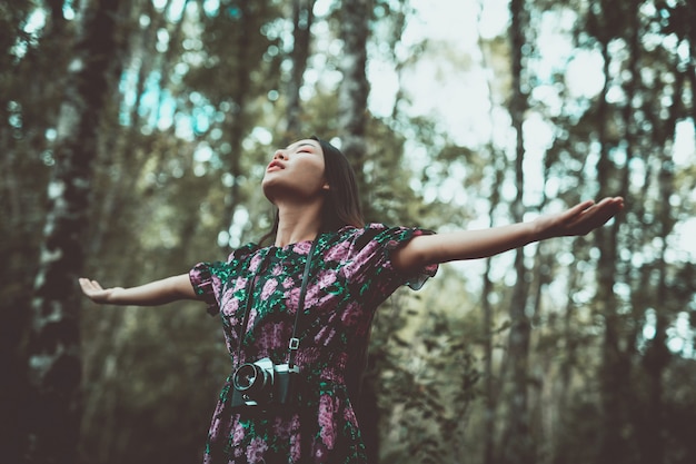 Foto gratuita una mujer moderna de pie en brazos con felicidad en el bosque.