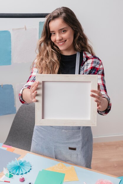 Mujer moderna que muestra el marco vacío blanco