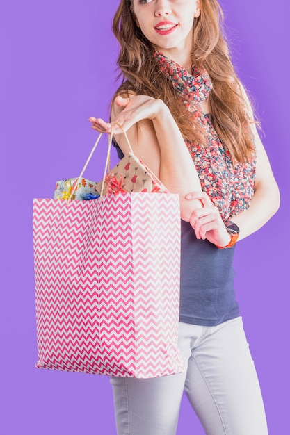 Mujer moderna que sostiene el bolso de compras lleno de regalo envuelto