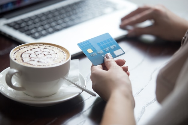 Mujer moderna que usa la tarjeta de crédito para el pago en línea. De cerca