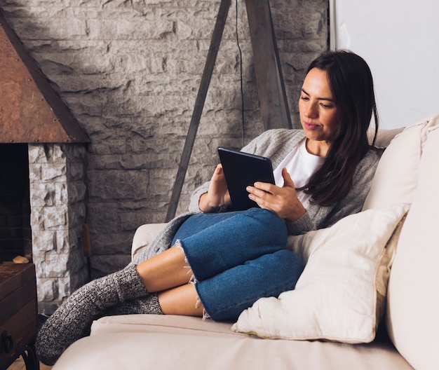 Mujer moderna sentada en el sofá usando la tablet