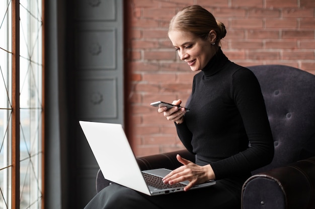 Mujer moderna sonriente que trabaja en la computadora portátil