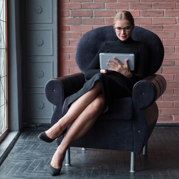 Mujer moderna con tableta en sofá