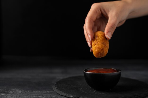 Mujer mojando una croqueta en ketchup