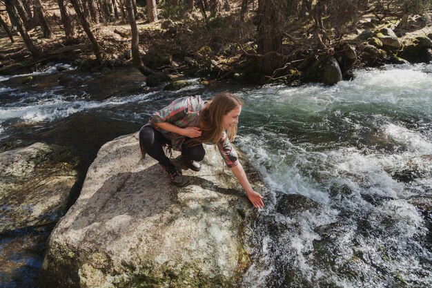 Mujer mojando su mano en el río