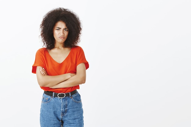 Mujer molesta con peinado afro posando en el estudio