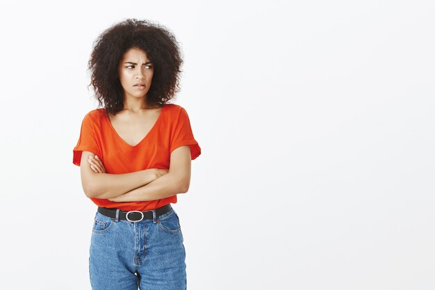 Mujer molesta con peinado afro posando en el estudio