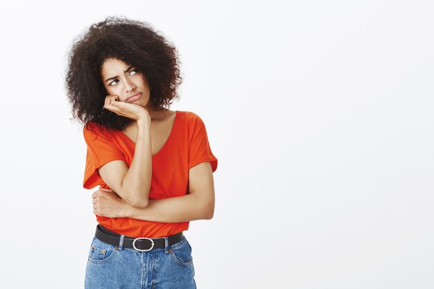 Mujer molesta con peinado afro posando en el estudio