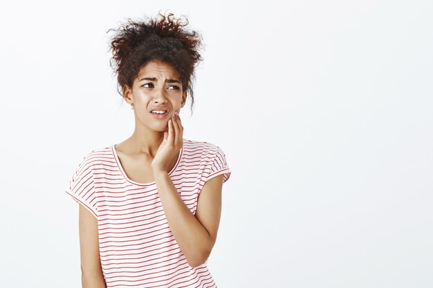 Mujer molesta preocupada con peinado afro posando en el estudio