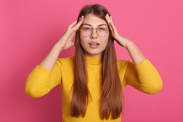 Mujer molesta que sufre de dolor de cabeza, tiene problemas en el trabajo, toca sus sienes y