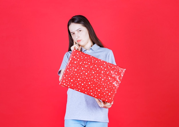 Mujer molesta sosteniendo caja de regalo y mirando a la cámara