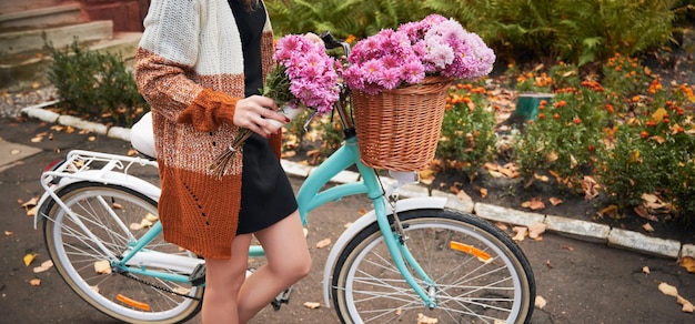 Mujer monta bicicleta con cesta de crisantemo rosa