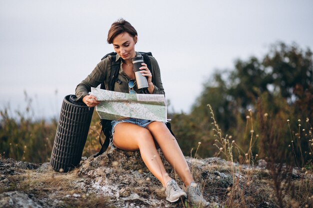 Mujer en montaña con bolsa de viaje mirando el mapa