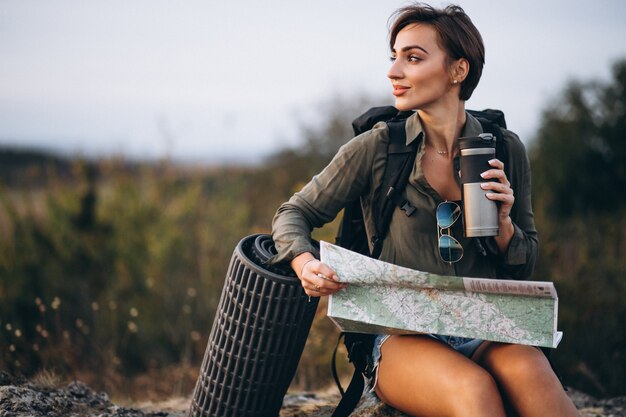 Mujer en montaña con bolsa de viaje mirando el mapa