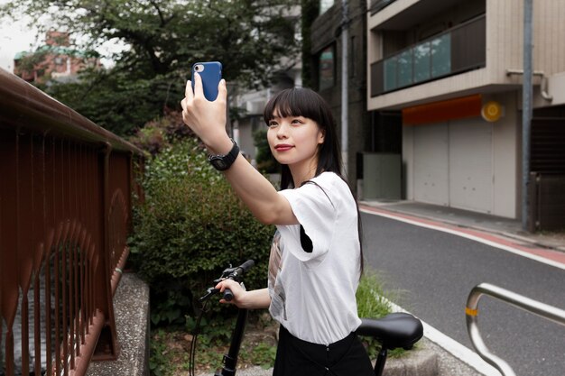 Mujer montando bicicleta en la ciudad y tomando selfie