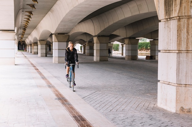 Mujer montando bicicleta debajo del puente