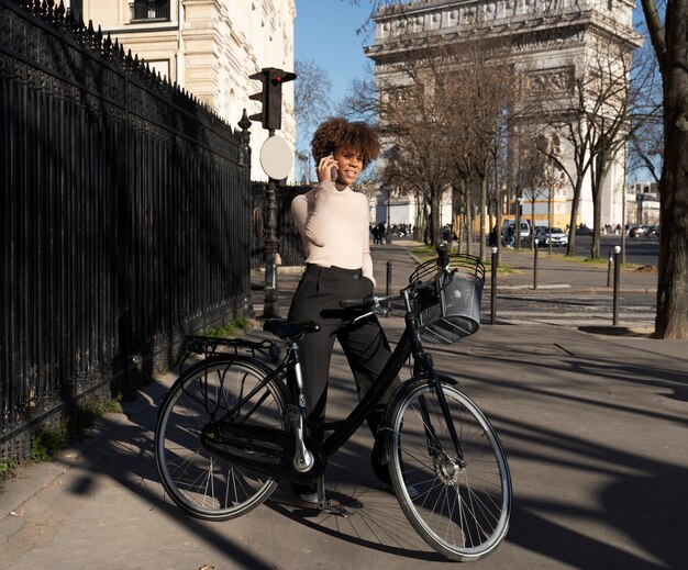 Mujer montando en bicicleta y hablando por teléfono inteligente en la ciudad de francia