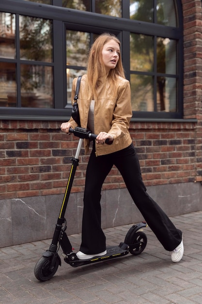 Mujer montando scooter eléctrico al aire libre en la ciudad
