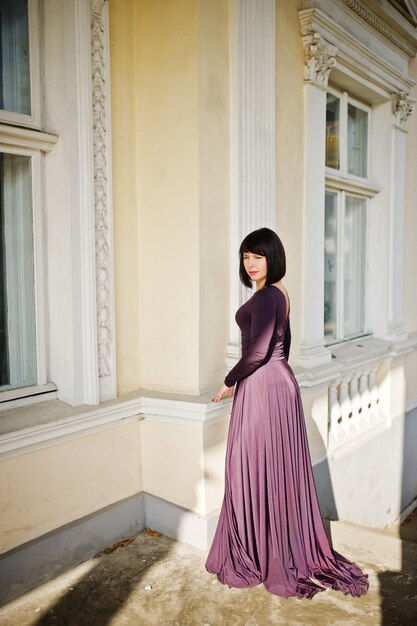 Mujer morena adulta en el vestido violeta fondo antigua casa vintage con escaleras