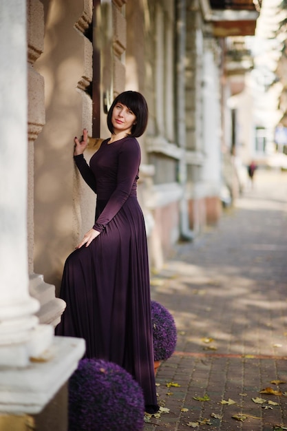 Mujer morena adulta en vestido violeta sobre fondo de otoño