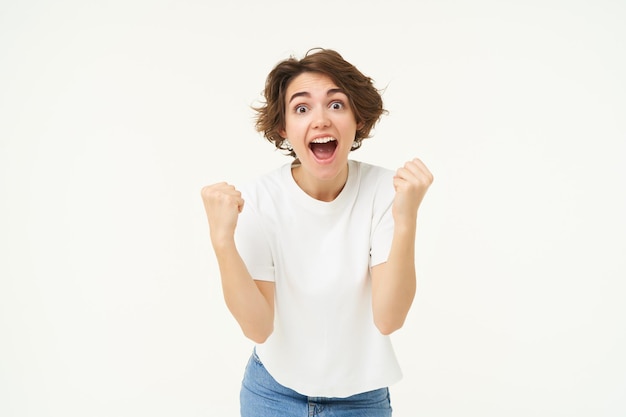 Mujer morena alegre ganando triunfando celebrando la victoria logra el objetivo se encuentra sobre blanco