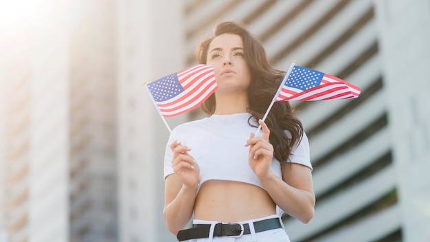 Mujer morena de ángulo bajo con banderas de Estados Unidos