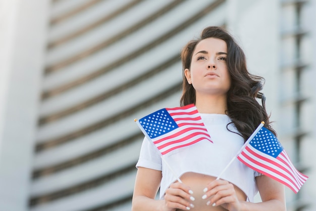 Mujer morena de ángulo bajo con dos banderas de Estados Unidos