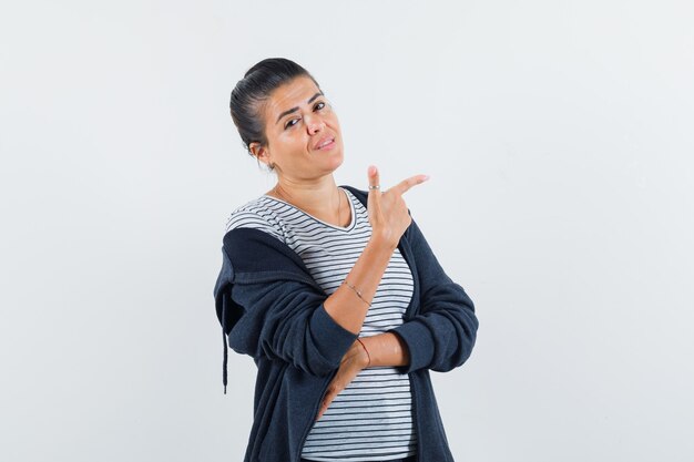 Mujer morena apuntando a un lado en camisa