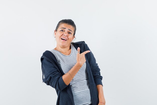 Mujer morena apuntando a un lado mientras habla en camisa