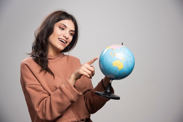 Mujer morena apuntando a un pequeño lugar en el mundo