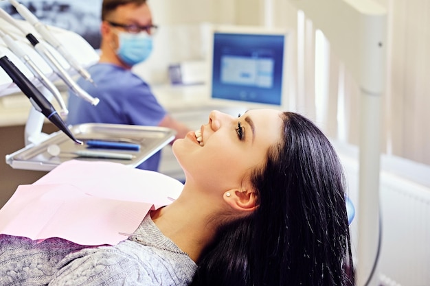 Mujer morena atractiva en una silla de dentista en una sala de estomatología.