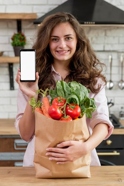 Mujer morena con bolsa de papel con alimentos sanos