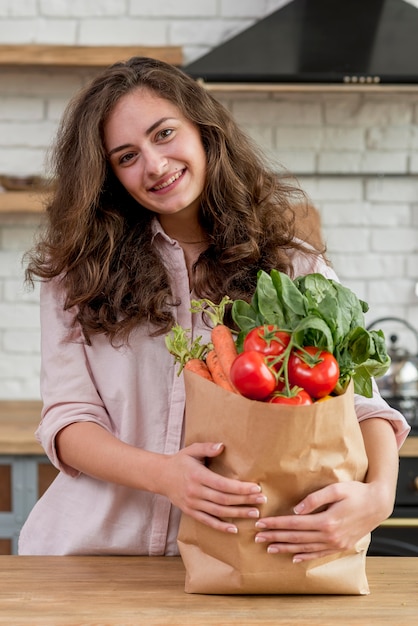 Mujer morena con bolsa de papel con alimentos sanos