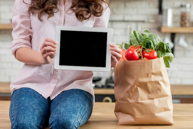 Mujer morena con bolsa de papel con alimentos sanos